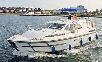 Das Hausboot Haines fährt über die Müritz vorbei am Hafendorf Müritz. 