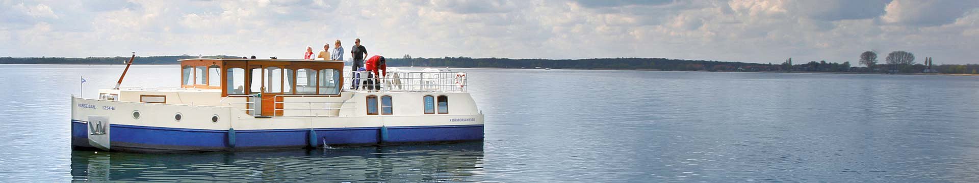 Das Hausboot Kormoran 1500 zeigt sich auf einen der vielen Seen der Mecklenburgischen Seenplatte von seiner besten Seite und erstrahlt im ruhigen Wasser.